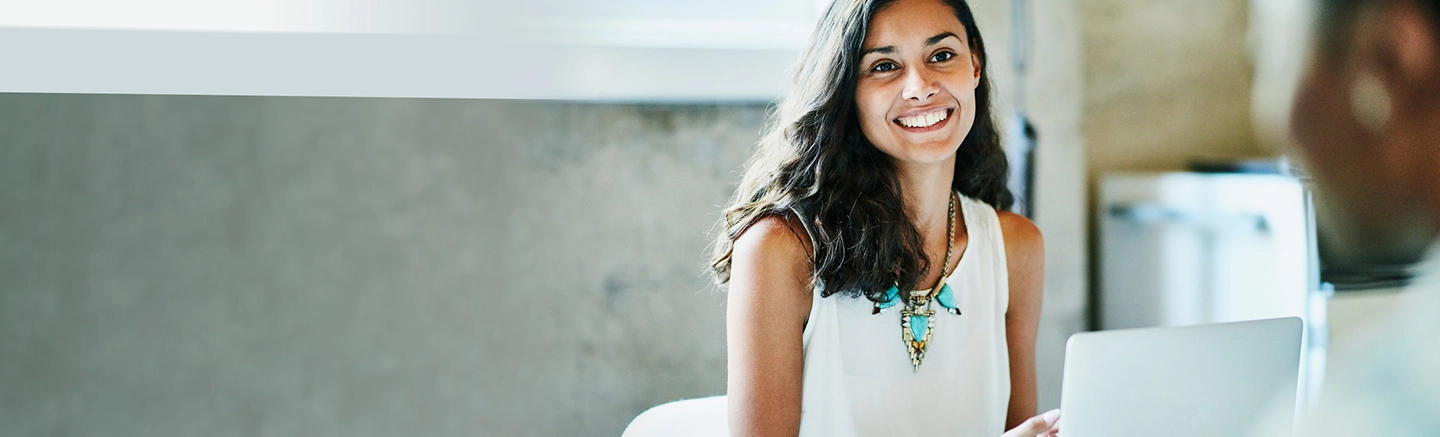 Human Resources manager with teal necklace talking with colleague across the table