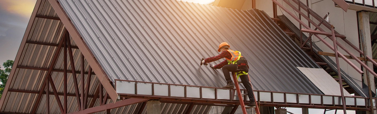 Construction worker with drill on metal roof