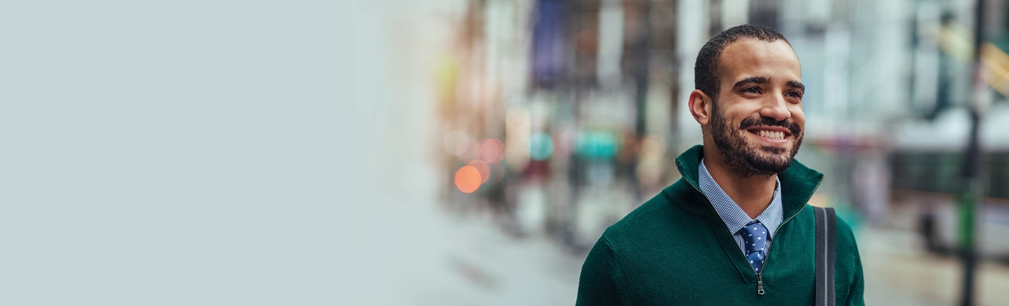 Man wearing green sweater and dress shirt and smiling