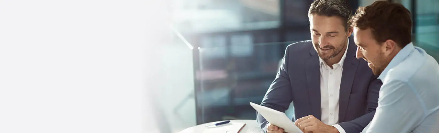 Two men in business attire looking at a tablet