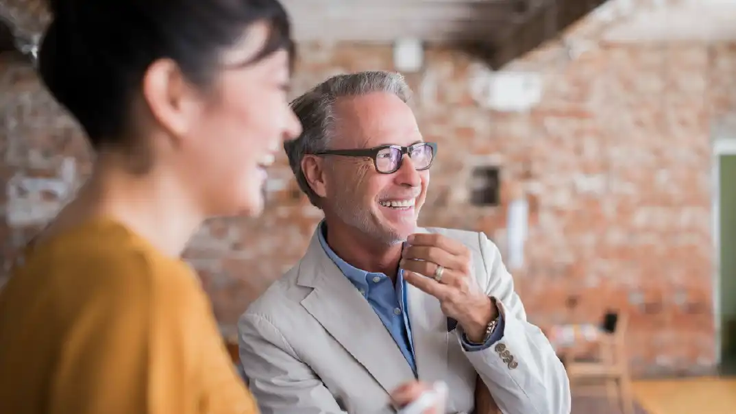Two people smile in an office.
