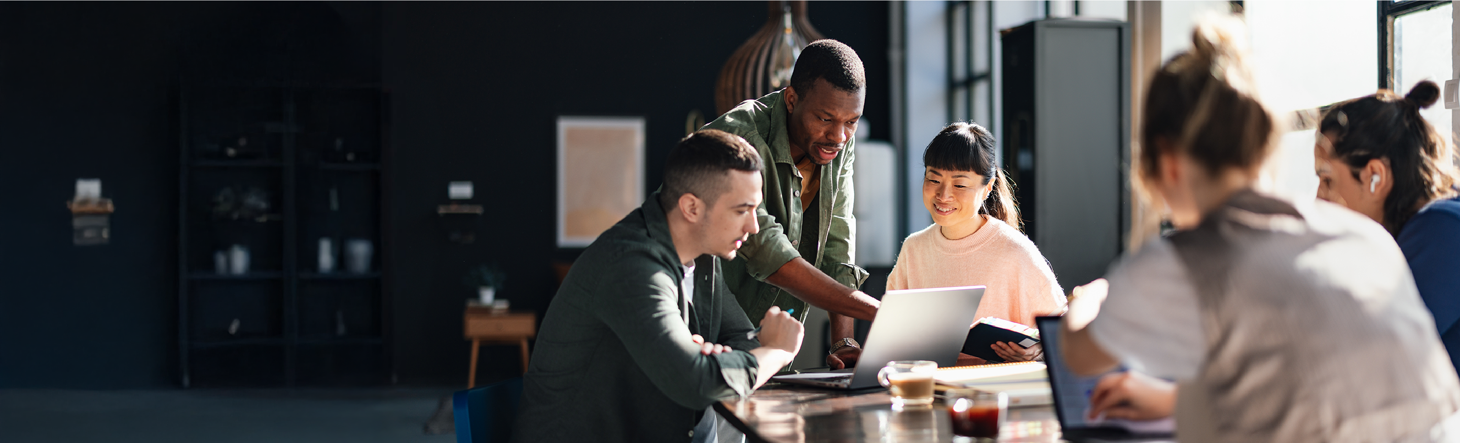 A group of people convene and discuss in a meeting as a man points to a computer.