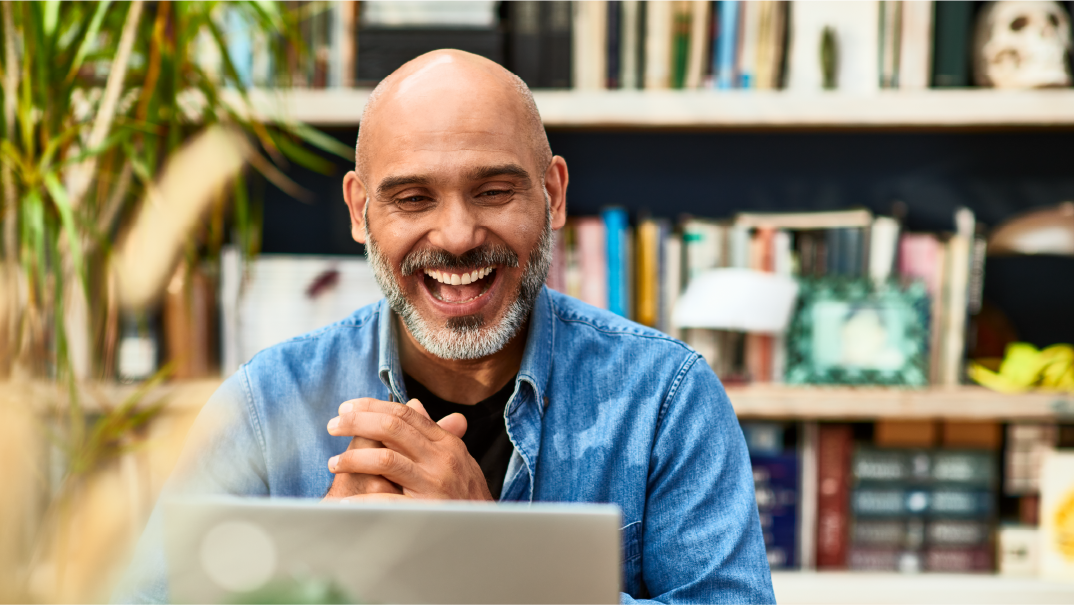 Hays 3-Step Interview Guide for job seekers: A man smiles and claps as he looks into his laptop. Behind him is a bookshelf.