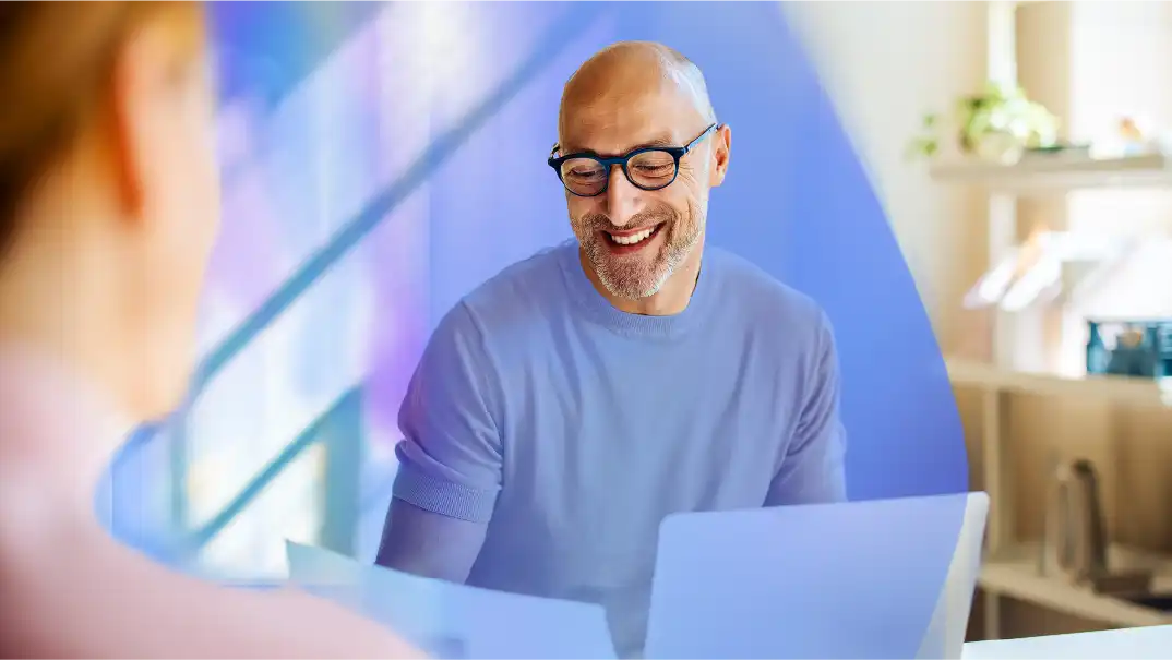 Hays 3-Step Interview Guide for job seekers: A man smiles as he looks at his resume, his laptop next to him. He is doing home office.